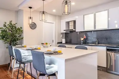 a kitchen with a table and chairs in a kitchen with white cabinets at Caniço Penthouse by Homie in Santa Cruz