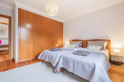 a bedroom with two beds and a wooden cabinet at Caniço Penthouse by Homie in Santa Cruz