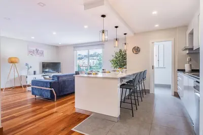 a kitchen and living room with a bar and a couch at Caniço Penthouse by Homie in Santa Cruz