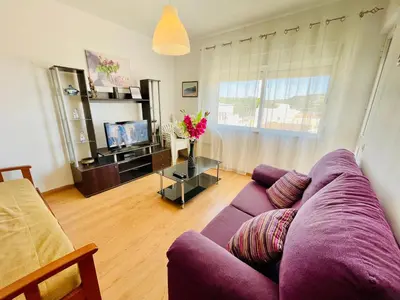 a living room with a purple couch and a tv at Apartamento Maria Fernanda, in the Centre of Luz in Luz