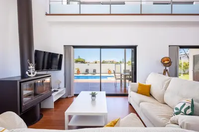 a living room with a white couch and a tv at Pontalaia Village in Sagres