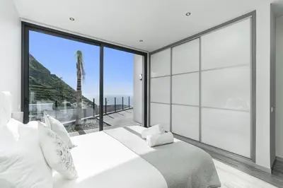 a bedroom with a large white bed and a large window at Villa Calheta Charm by Villa Plus in Arco da Calheta