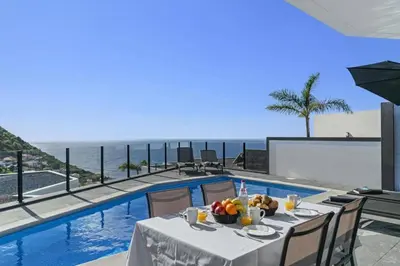 a table with fruit on it next to a swimming pool at Villa Calheta Charm by Villa Plus in Arco da Calheta