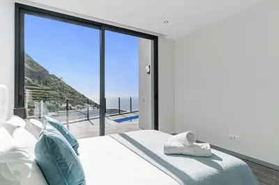 a bedroom with a bed with a view of the ocean at Villa Calheta Charm by Villa Plus in Arco da Calheta