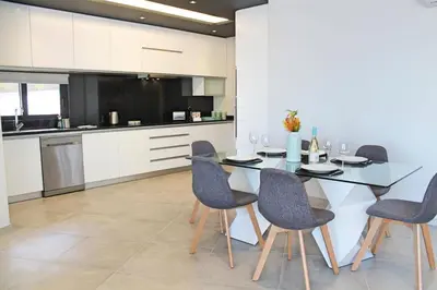 a kitchen with a glass table and chairs in a kitchen at Villa Calheta Charm by Villa Plus in Arco da Calheta