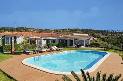 a swimming pool in front of a house at Villa Theos House by Villa Plus in Fajã da Ovelha