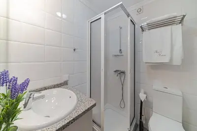 a white bathroom with a sink and a shower at Villa Theos House by Villa Plus in Fajã da Ovelha