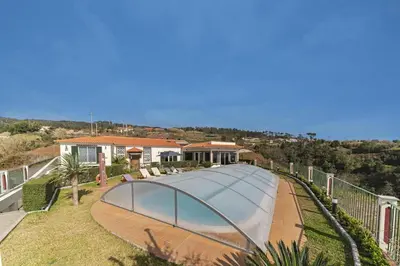 a swimming pool with a glass roof on a house at Villa Theos House by Villa Plus in Fajã da Ovelha