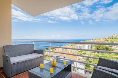 a balcony with a table and chairs and the ocean at Canico Vip Lodging by Homie in Santa Cruz