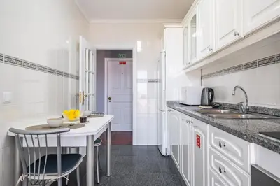 a kitchen with white cabinets and a sink and a table at Canico Vip Lodging by Homie in Santa Cruz