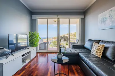 a living room with a leather couch and a large window at Canico Vip Lodging by Homie in Santa Cruz