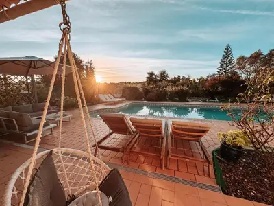 a swing with two chairs and a swimming pool at Villa Rubix in Luz