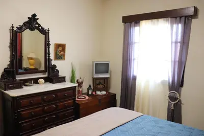 a bedroom with a dresser and a mirror and a bed at Suites Pinto Coelho in Caniço