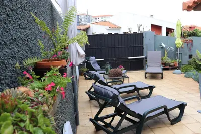 a patio with a bunch of chairs and plants at Suites Pinto Coelho in Caniço