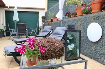 a glass table with flowers and a fish tank on a patio at Suites Pinto Coelho in Caniço