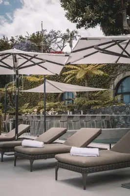 a row of lounge chairs with umbrellas at QUINTA TORRINHA GARDEN Apartment in Funchal