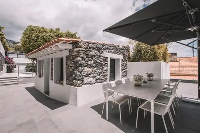 a patio with a table and chairs and an umbrella at QUINTA TORRINHA GARDEN Apartment in Funchal