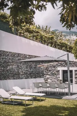 a patio with a table and chairs and an umbrella at QUINTA TORRINHA GARDEN Apartment in Funchal