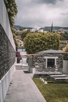 a patio with tables and chairs on the side of a building at QUINTA TORRINHA GARDEN Apartment in Funchal