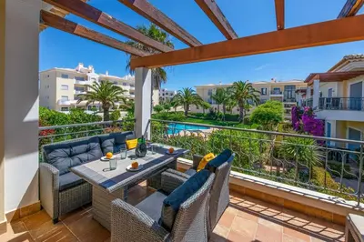 a balcony with a table and chairs and a view of the pool at Casa Palmeira in Lagos