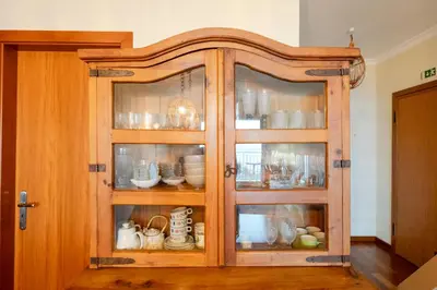 a wooden cabinet with glass doors with dishes in it at Caniço Quintas III by Trip2Portugal in Caniço