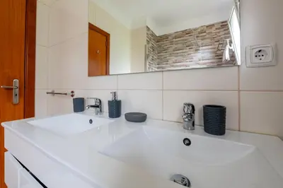 a bathroom with a white sink and a mirror at Caniço Quintas III by Trip2Portugal in Caniço