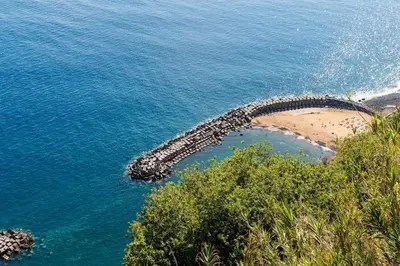 a stone path in the water next to a beach at Casa Miradouro do Pigarro, Sunny Apartment in Calheta