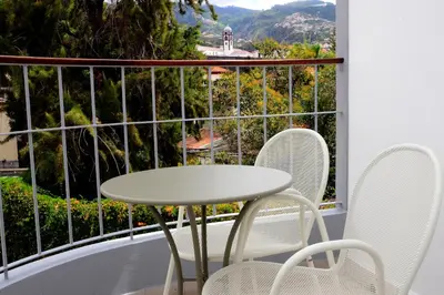a table and chairs on a balcony with a view at VILA ALEGRIA in Funchal