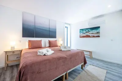 a white bedroom with a bed with blue pillows at Frontline Seaview Apartment in Budens