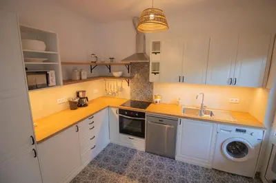 a kitchen with white cabinets and a washer and sink at Casa Jana 5 Bedroom House for 12 with Ocean View Terrace near the Beach in Burgau