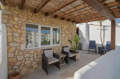 a patio with chairs and a stone wall at Casa Jana 5 Bedroom House for 12 with Ocean View Terrace near the Beach in Burgau