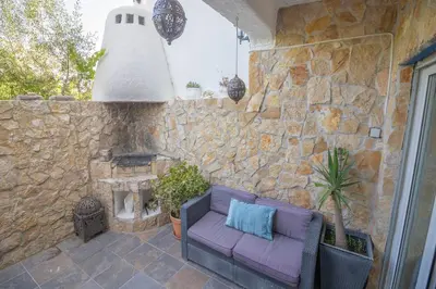 a patio with a purple couch and a stone wall at Casa Jana 5 Bedroom House for 12 with Ocean View Terrace near the Beach in Burgau
