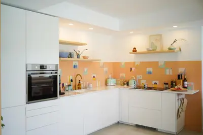 a kitchen with white cabinets and an orange tile wall at Birds of Paradise - Boutique Surf Lodge in Aljezur
