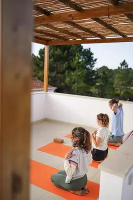 three girls sitting on the floor in a yoga class at Birds of Paradise - Boutique Surf Lodge in Aljezur