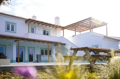 a large white house with a wooden structure at Birds of Paradise - Boutique Surf Lodge in Aljezur