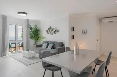 a white living room with a table and a couch at Intelsol Calheta Apartments by An Island Apart in Calheta