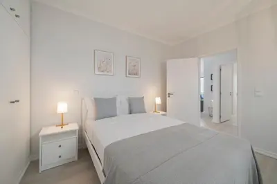 a white bedroom with a large bed and two lamps at Intelsol Calheta Apartments by An Island Apart in Calheta