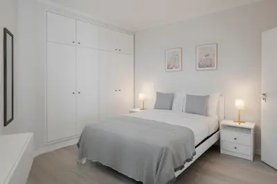 a white bedroom with a white bed and two lamps at Intelsol Calheta Apartments by An Island Apart in Calheta