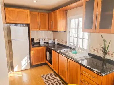 a kitchen with wooden cabinets and a white refrigerator at Casa Torbit, Apartment in Arco da Calheta in Arco da Calheta