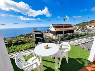 a white table and chairs on a balcony with the ocean at Casa Torbit, Apartment in Arco da Calheta in Arco da Calheta