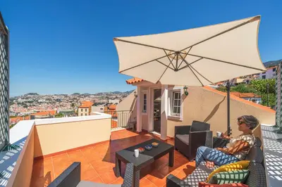 a man sitting on a balcony with an umbrella at Vila Boa Vista by An Island Apart in Funchal