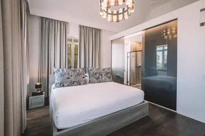 a bedroom with a white bed with a chandelier at QUINTA TORRINHA PANORAMA Apartment in Funchal