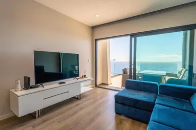 a living room with a blue couch and a television at FLH Amazing Ocean View with Balcony in Santa Cruz