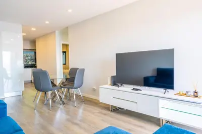 a living room with a tv and a table with chairs at FLH Amazing Ocean View with Balcony in Santa Cruz