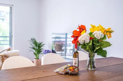 a bottle of wine and a vase of flowers on a table at Lovely apartment at the best location in Funchal in Funchal