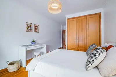 a bedroom with a white bed and a wooden cabinet at Lovely apartment at the best location in Funchal in Funchal