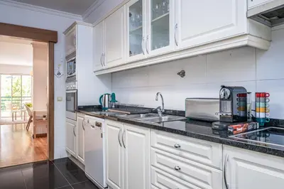 a kitchen with white cabinets and a sink at Lovely apartment at the best location in Funchal in Funchal