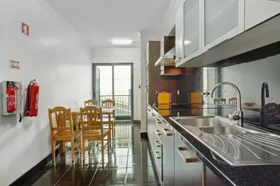 a kitchen with a sink and a table with chairs at Costa Avila 2 in Caniço