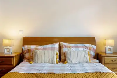 a bedroom with a bed with two night stands and two lamps at Costa Avila 2 in Caniço