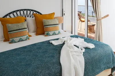 a bed with a blue comforter and pillows on it at Yeotown Madeira Wellness Hotel and Nature Stay in Arco da Calheta